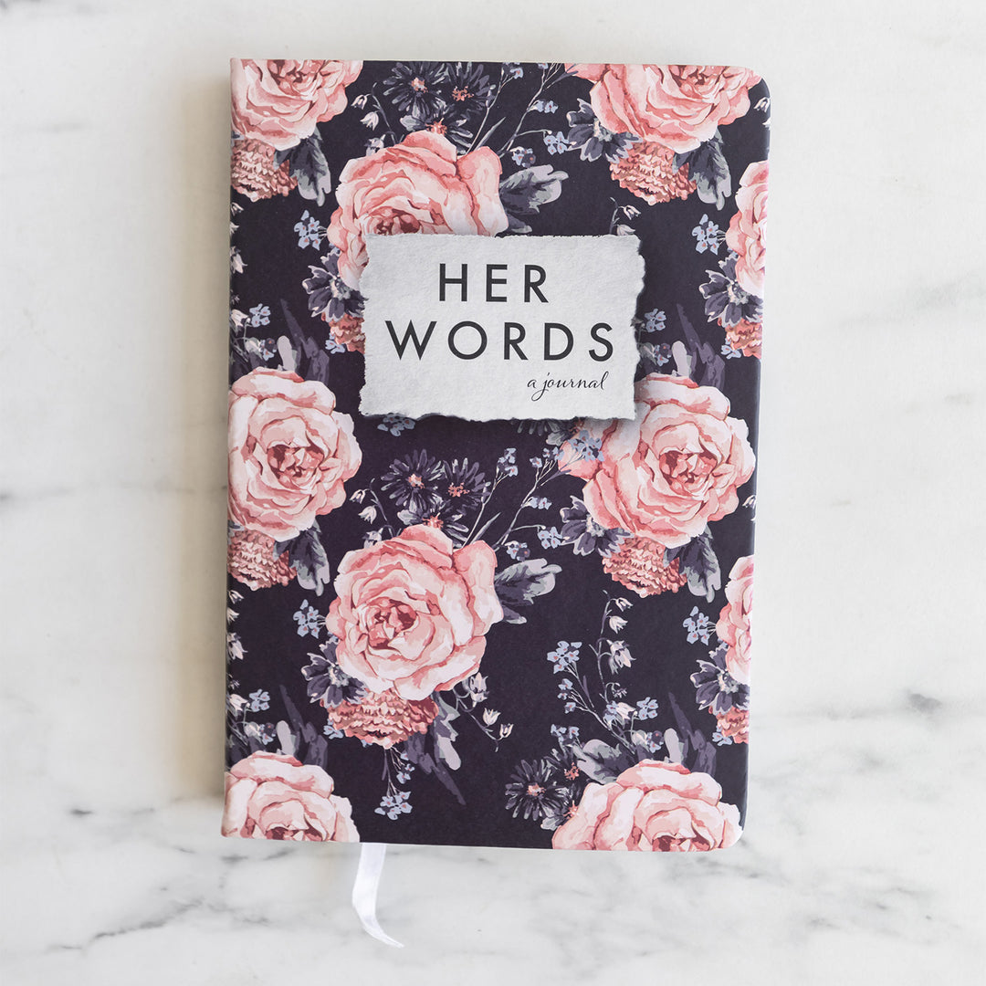 A pink rose-patterned journal that says Her Words a journal.