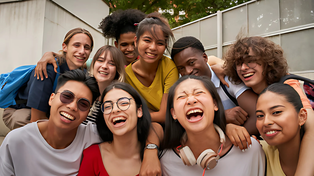 A diverse group of young people laughing and smiling outdoors, embracing each other in a close-knit and joyful moment.