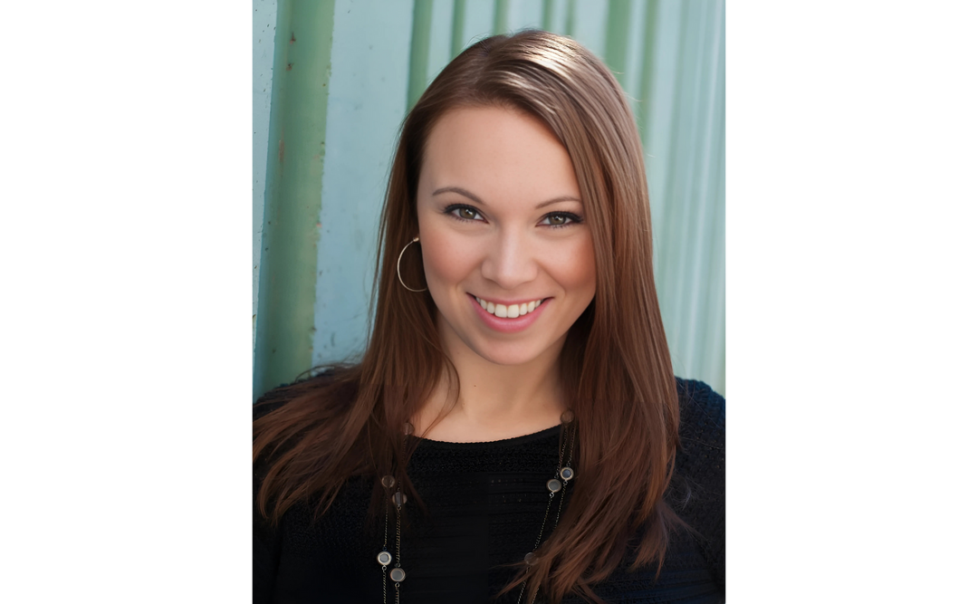 Author Suzanne Young smiling warmly, with long brown hair, wearing a black top and hoop earrings against a teal background.