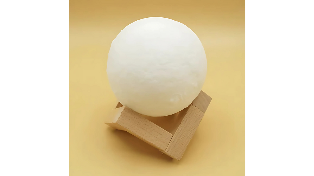 A white spherical lamp placed on a simple wooden stand against a light yellow background.