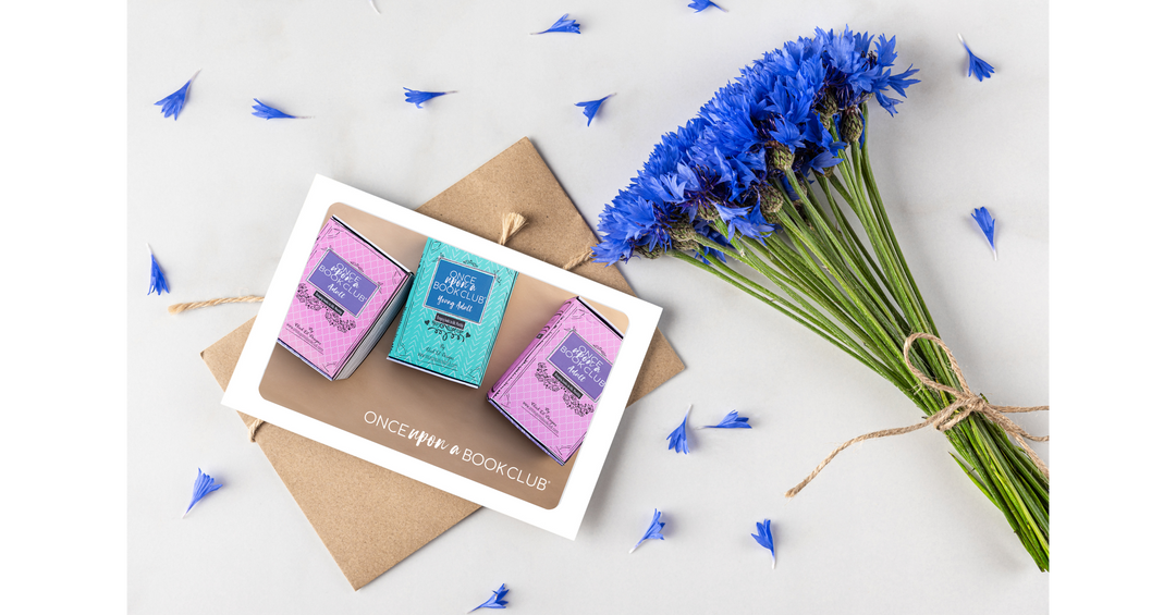 Blue flowers, kraft envelope, and a book box card arranged in a delicate floral flat lay.