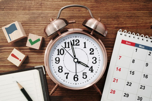 Alarm clock, calendar, and checklist on a desk, symbolizing time management and scheduling.