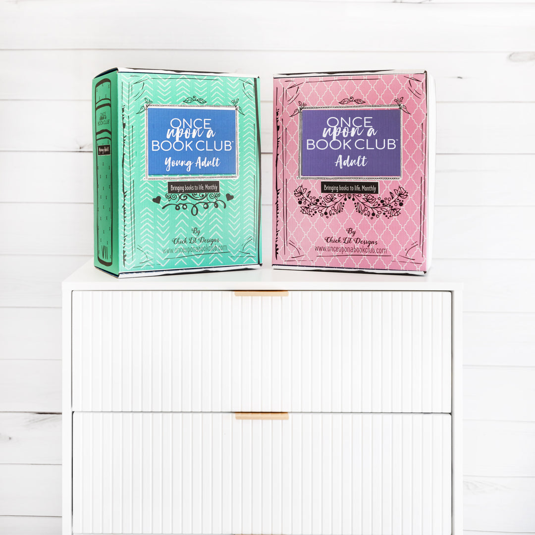 Two book-shaped-boxes from 'Once Upon a Book Club' series on dresser on a white background.