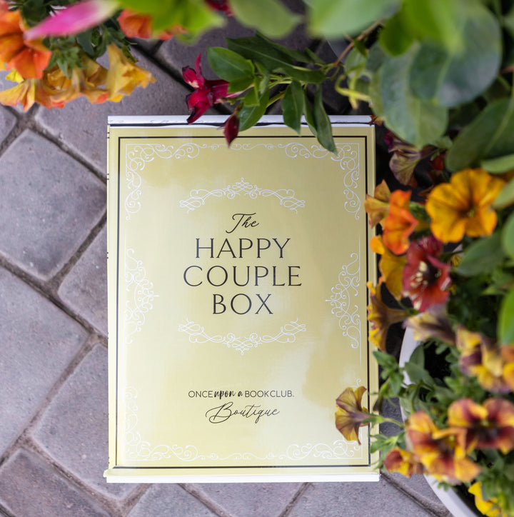 A yellow Happy Couple box sits under an array of colorful flowers and greenery.