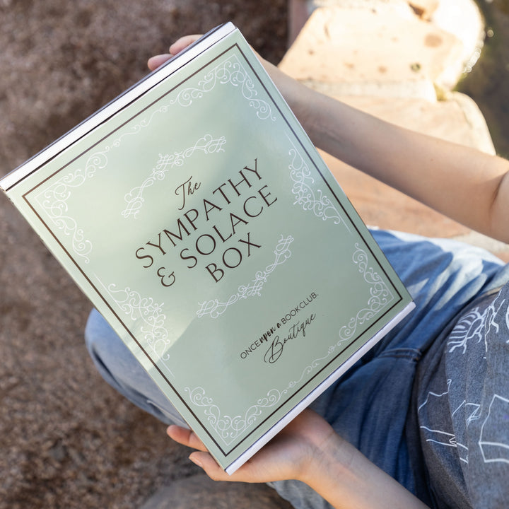 The sage green Sympathy & Solace box is held in someone's hands.