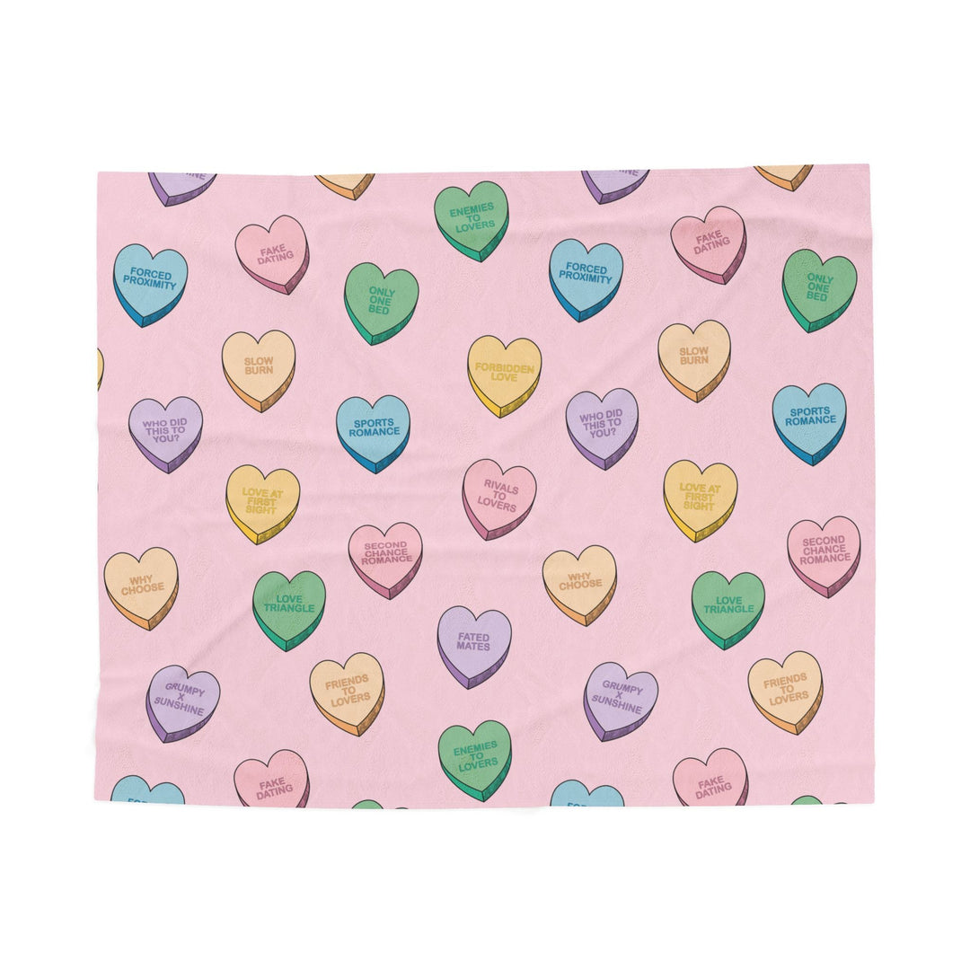 Pink blanket with colorful heart-shaped candy patterns on a white background
