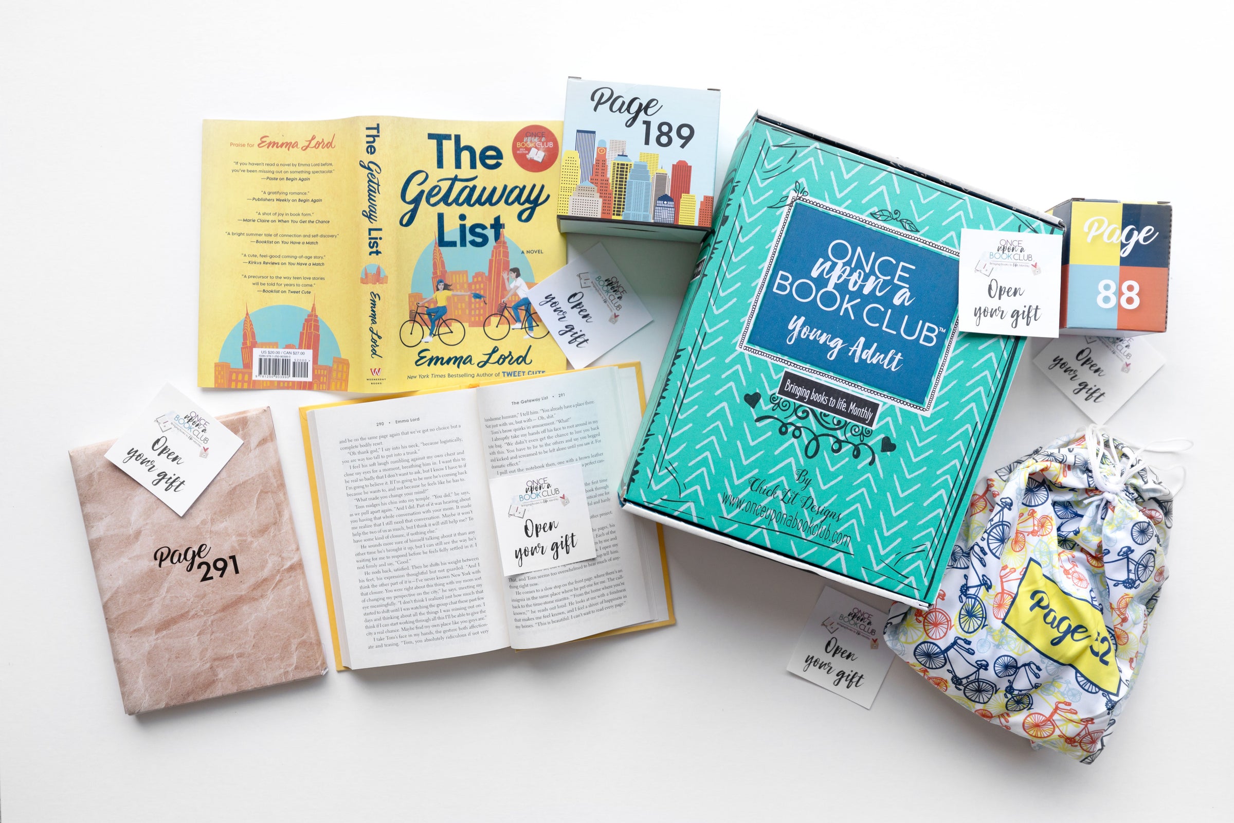 A green Once Upon a Book Club box sits next to an open book. The book has an 'open your gift' sticky note on the page. Wrapped gifts labeled with page numbers and many other open your gift sticky notes surround the open book emphasizing that you open the gifts as you read!