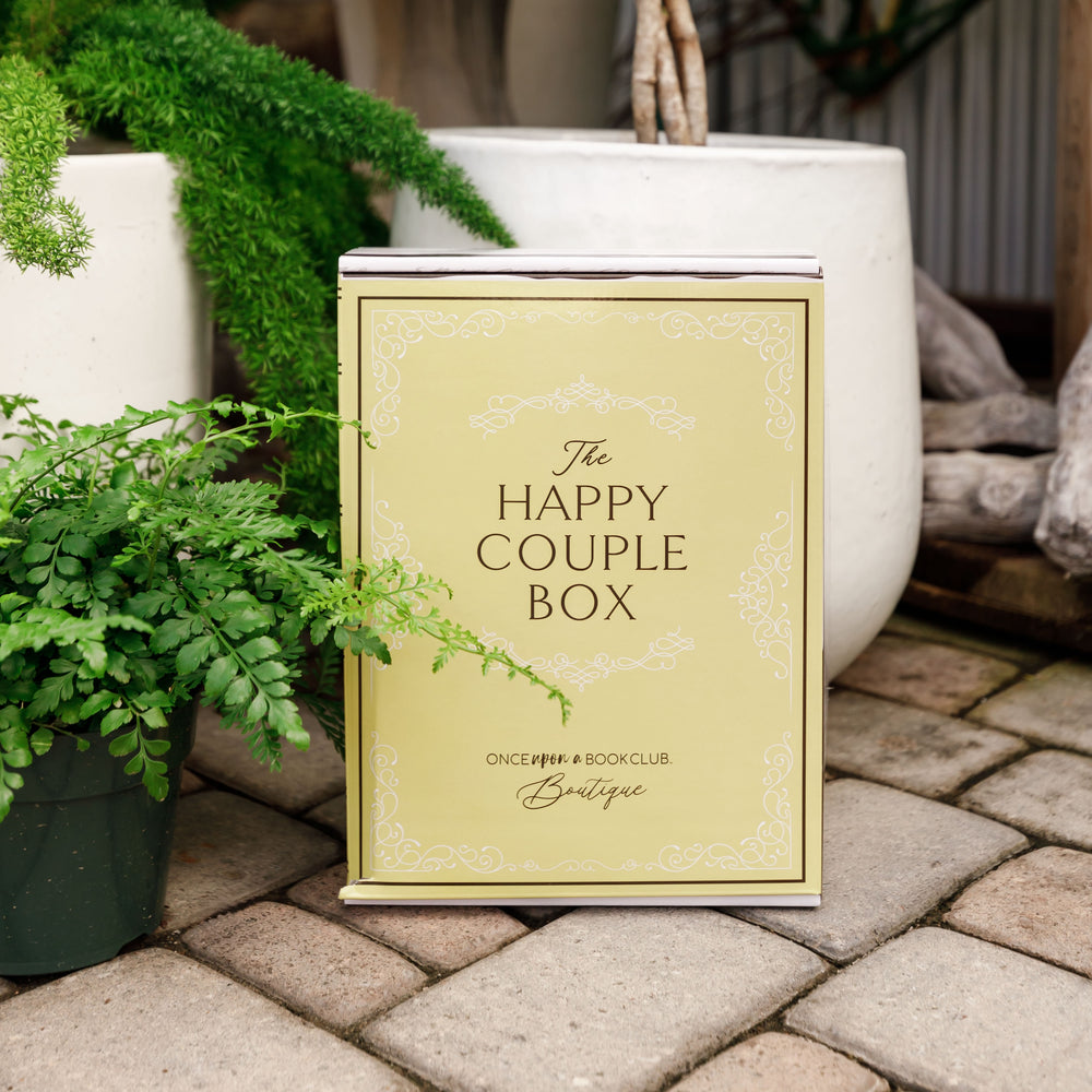 A yellow Happy Couple box sits outdoors surrounded by greenery.