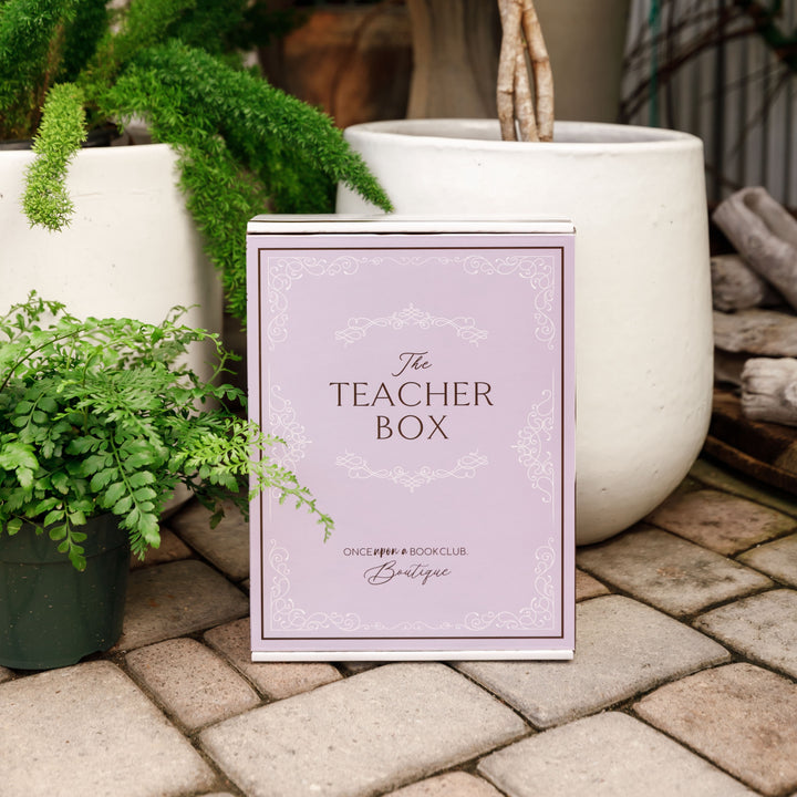 A light purple Teacher box sits outdoors surrounded by greenery.