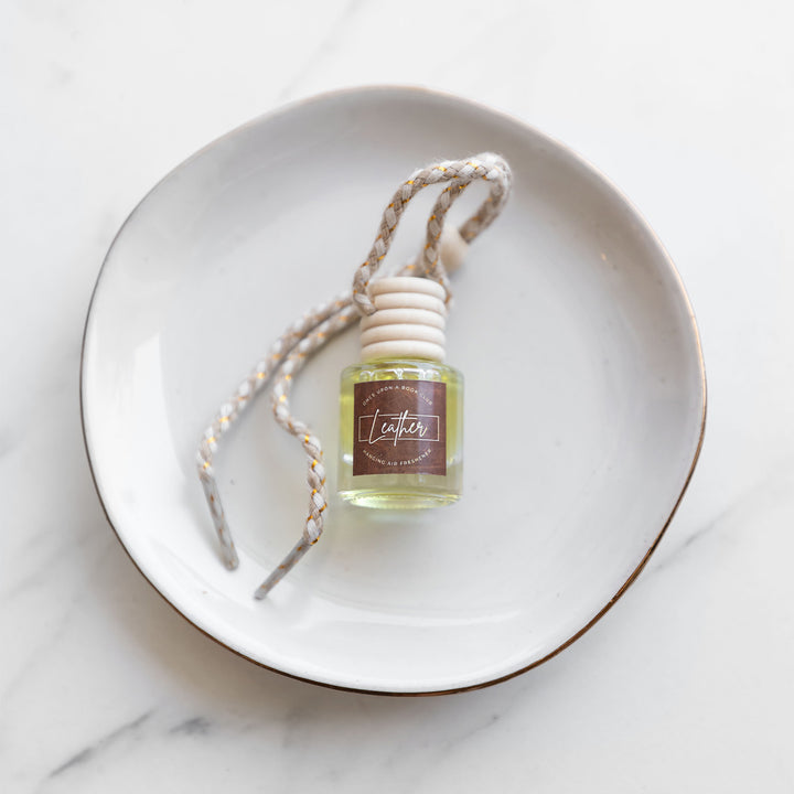 a bottle of leather scented air freshener in a hanging car diffuser.