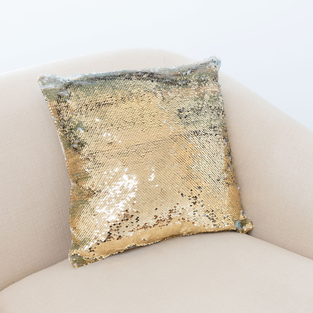 A gold sequin pillow on a pink chair.