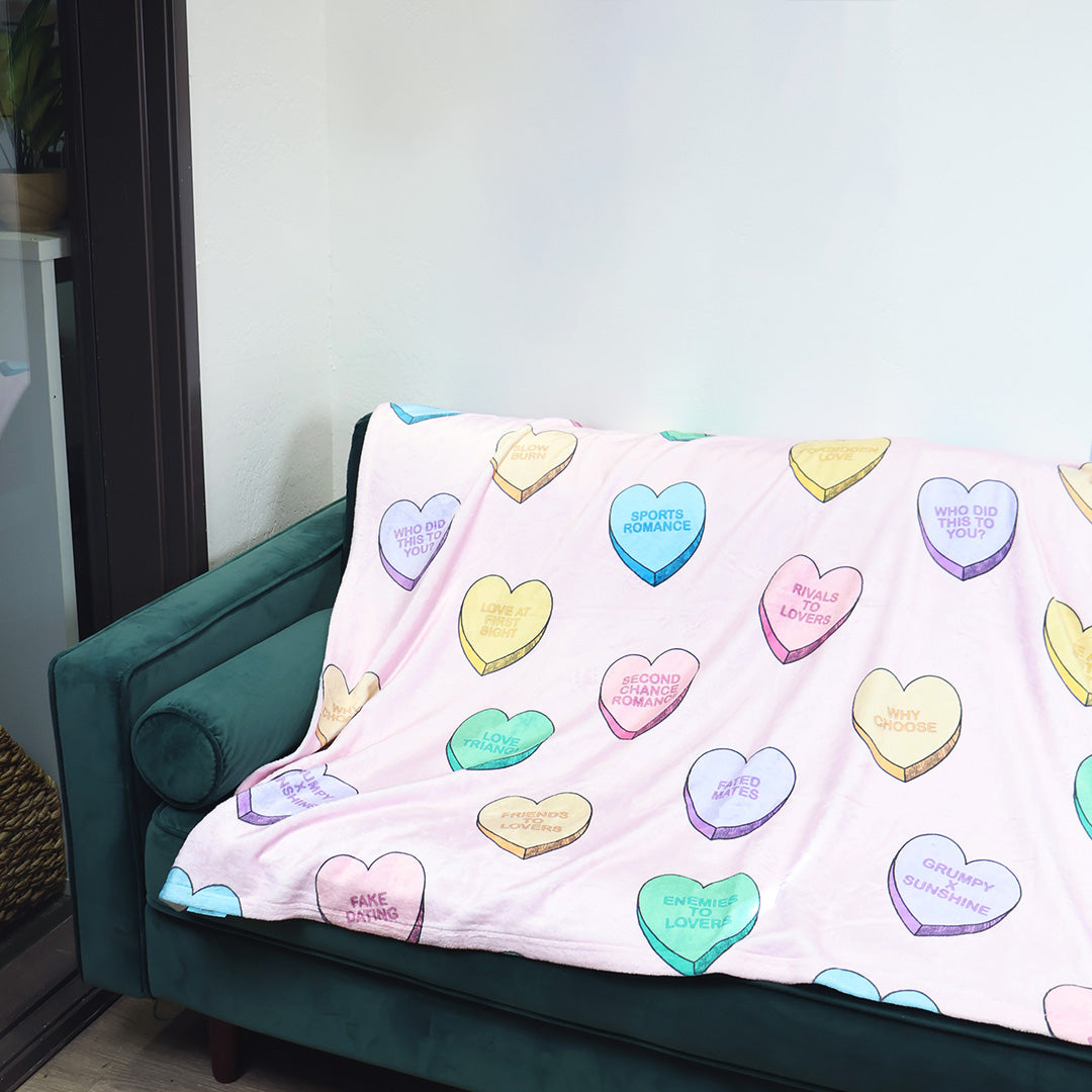 Colorful heart-patterned blanket draped over a green couch.