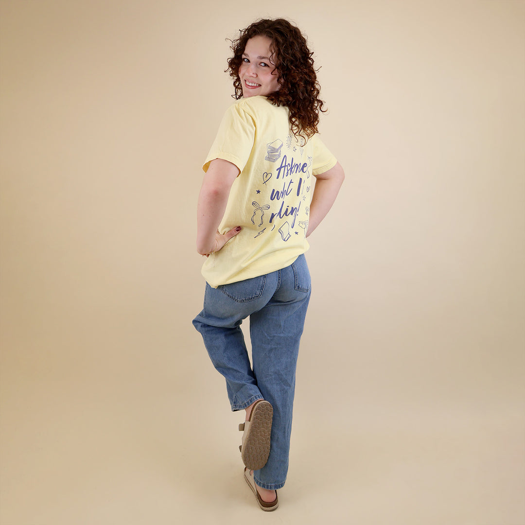 A woman wearing yellow t-shirts with 'Booked & Busy' on the front and 'Ask Me What I'm Reading' on the back surrounded by book-themed doodles.