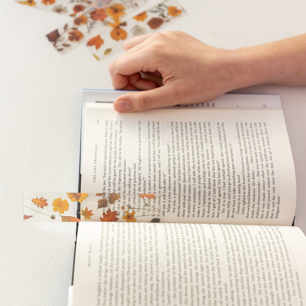 A set of five pressed flower bookmarks with one inside the book.