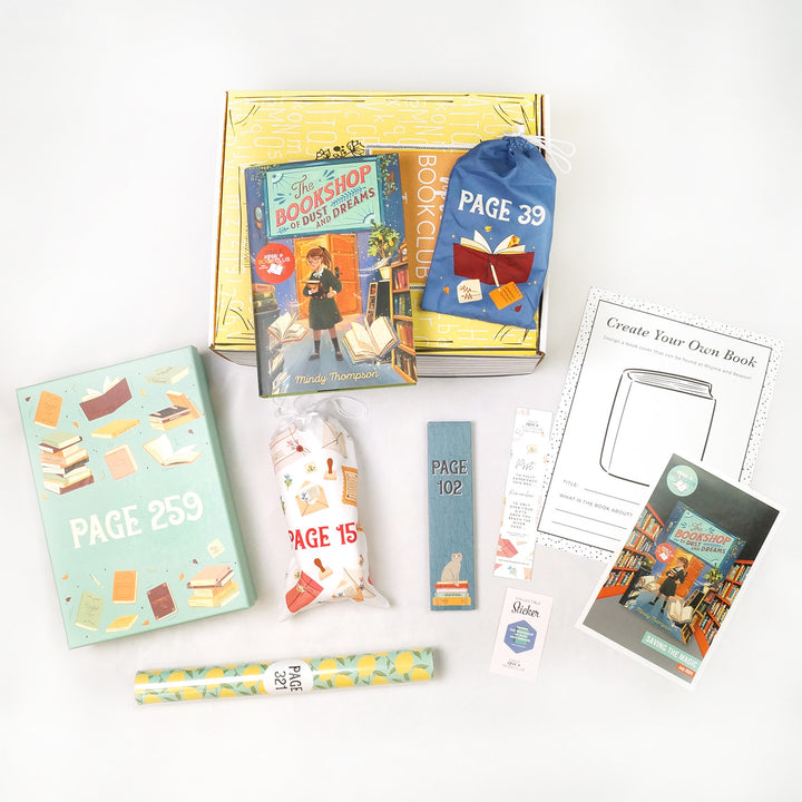 A hardcover copy of The Bookshop of Dust and Dreams by Mindy Thompson sits on a yellow Once Upon a Book Club tween box. This box is surrounded by wrapped gifts labeled with page numbers in addition to paperwork including a signed bookplate from the author, bookmark, activity sheet, and matching collectible sticker.