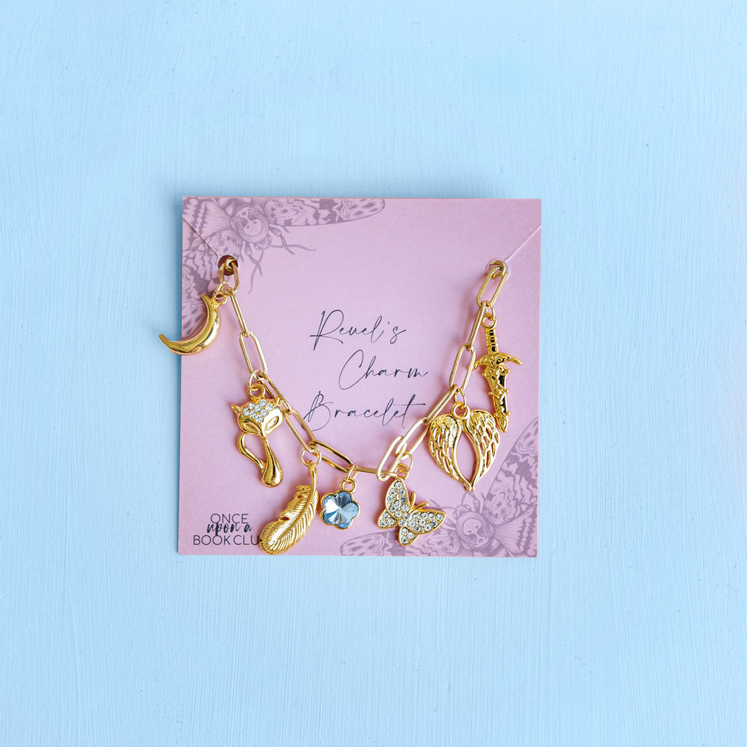 A gold charm bracelet with charms of a moon, cat, feather, butterfly, wings, and a sword all in gold