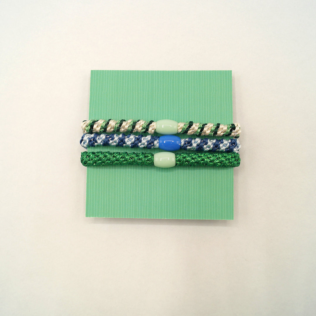 a set of three stretchy elastic bracelets on a green card.