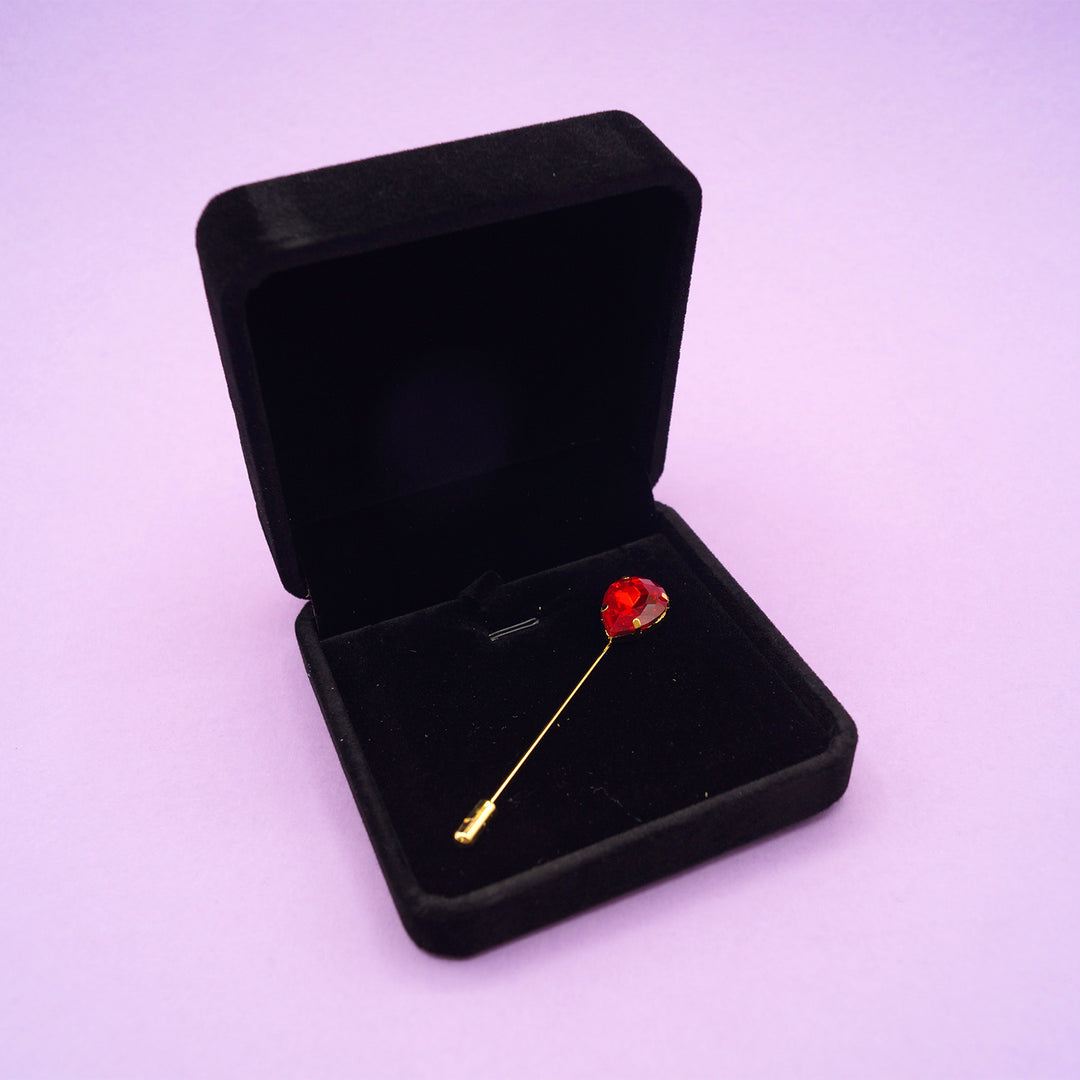 the red teardrop straight pin brooch sitting in a black velvet box.