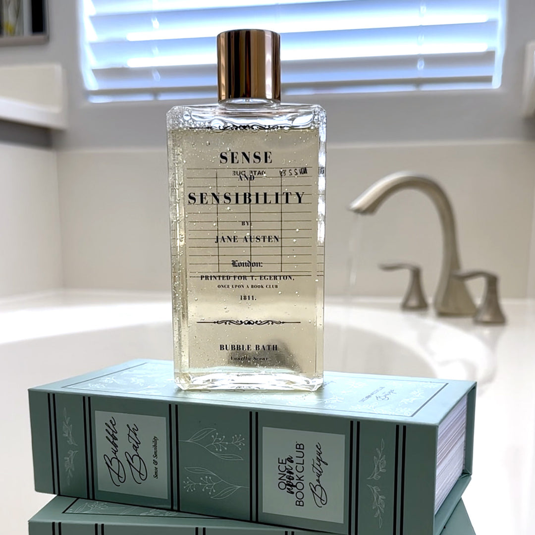 A bottle of bubble bath stands on top of the green floral box it is shipped in. The background is a bathtub faucet turned on a filling a white tub with water.