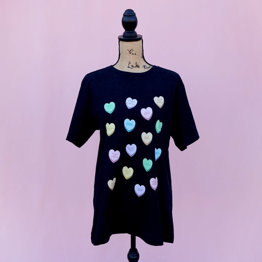 Black dress with colorful candy hearts with tropes on a mannequin against a pink background