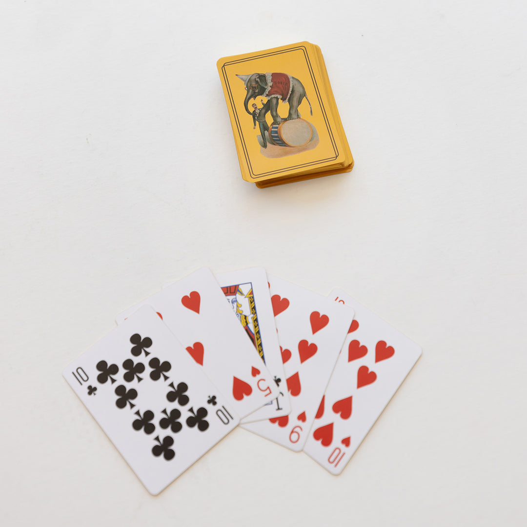 A stack of yellow playing cards with an image of a circus elephant on the back. Five cards are fanned out below it