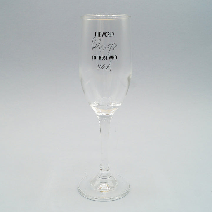 a clear champagne flute with the quote The World Belongs to Those Who Read