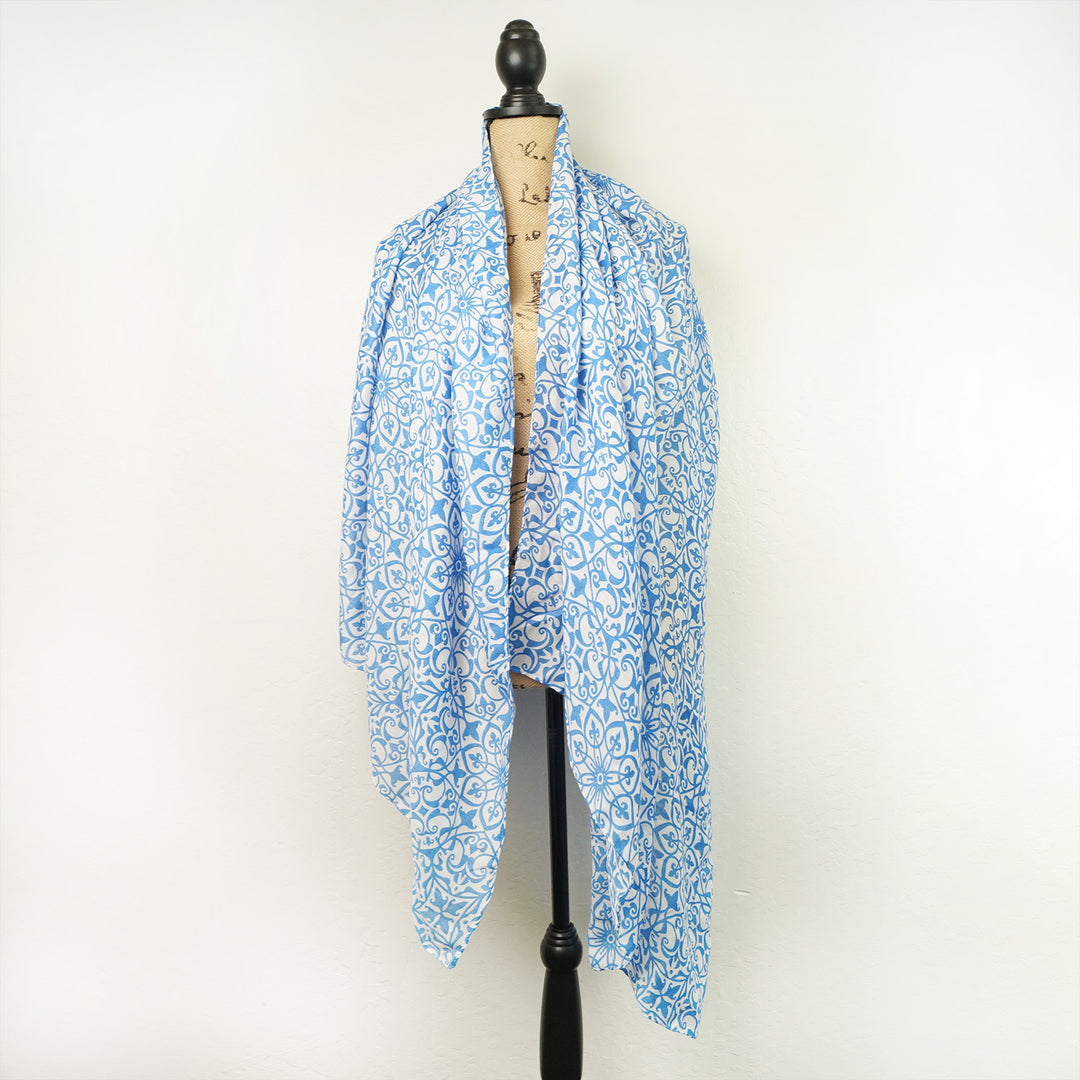 An oversized blue and white scarf hangs on a mannequin.