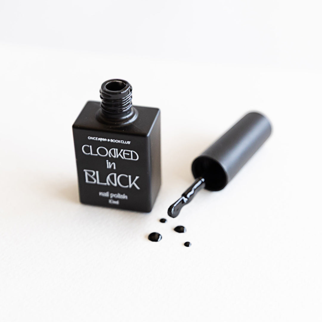 A black bottle of black nail polish labeled Once Upon a Book Club Cloaked in Black nail polish. 