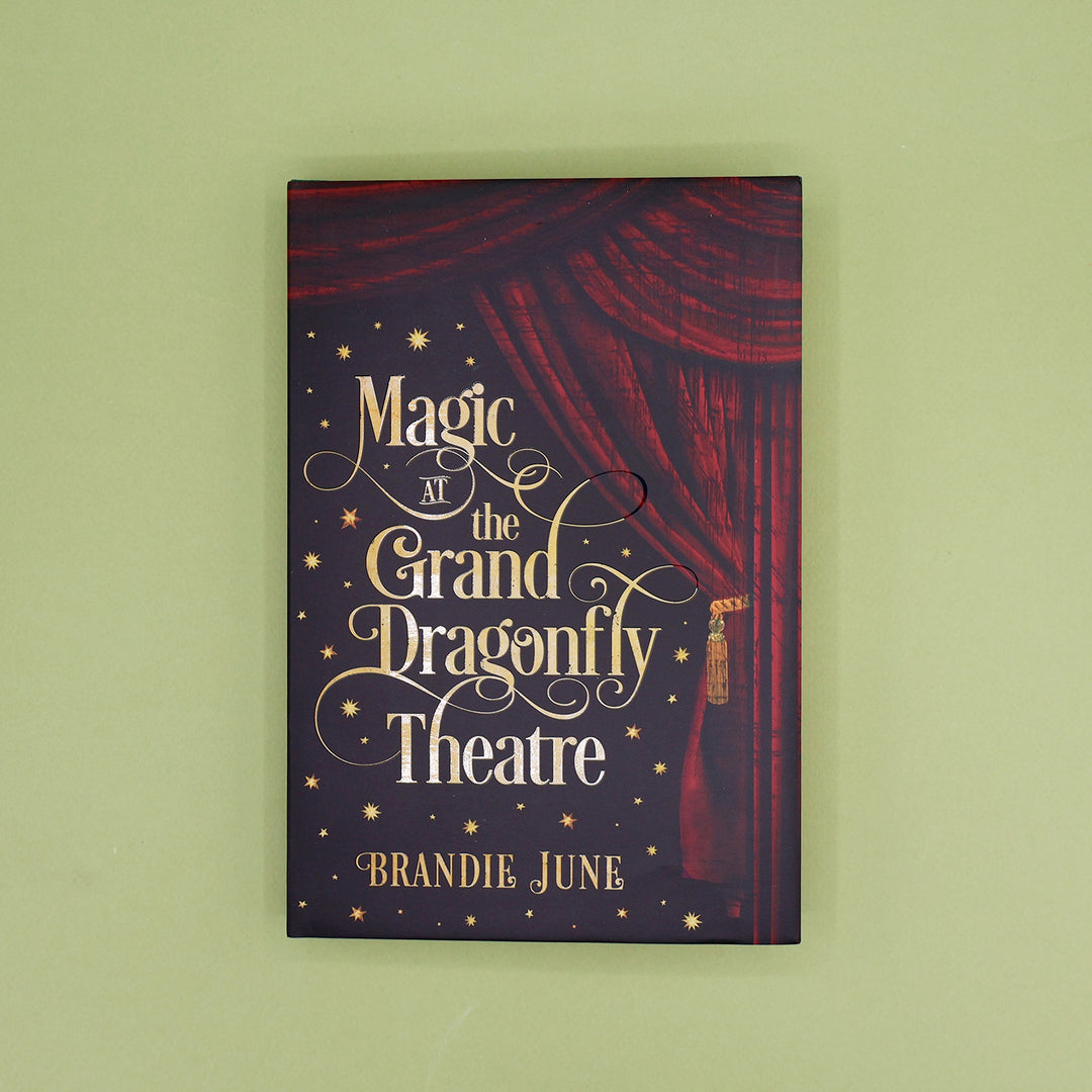 Book cover of 'Magic at the Grand Dragonfly Theatre' by Brandie June with red curtain design on a green background