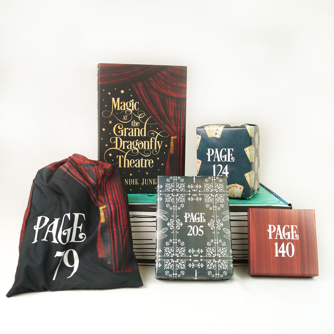 A hardcover copy of Magic at the Grand Dragonfly Theatre by Brandie June surrounded by wrapped gifts labeled with page numbers