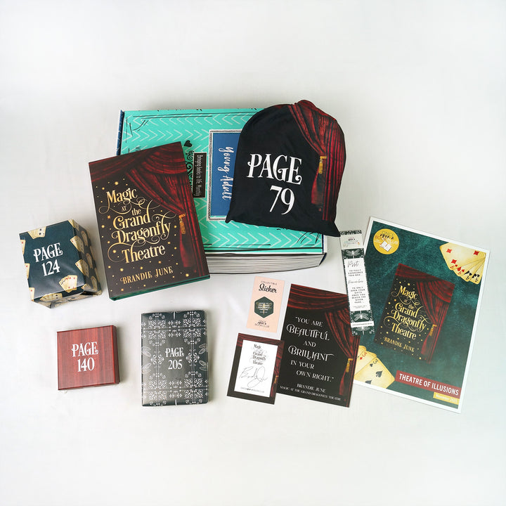 A hardcover copy of Magic at the Grand Dragonfly Theatre by Brandie June surrounded by wrapped gifts labeled with page numbers and paper items.