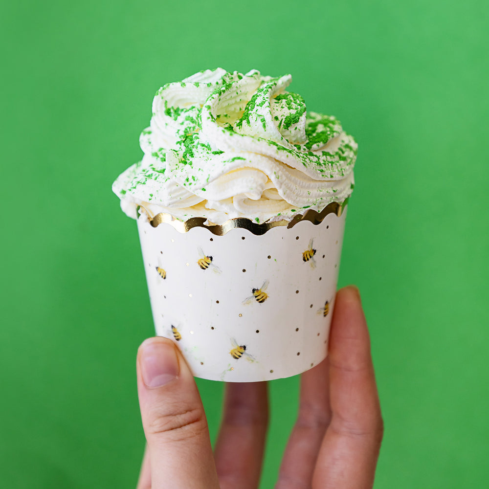 A hand holds up a cupcake that is decorated with the edible green shimmer dust.
