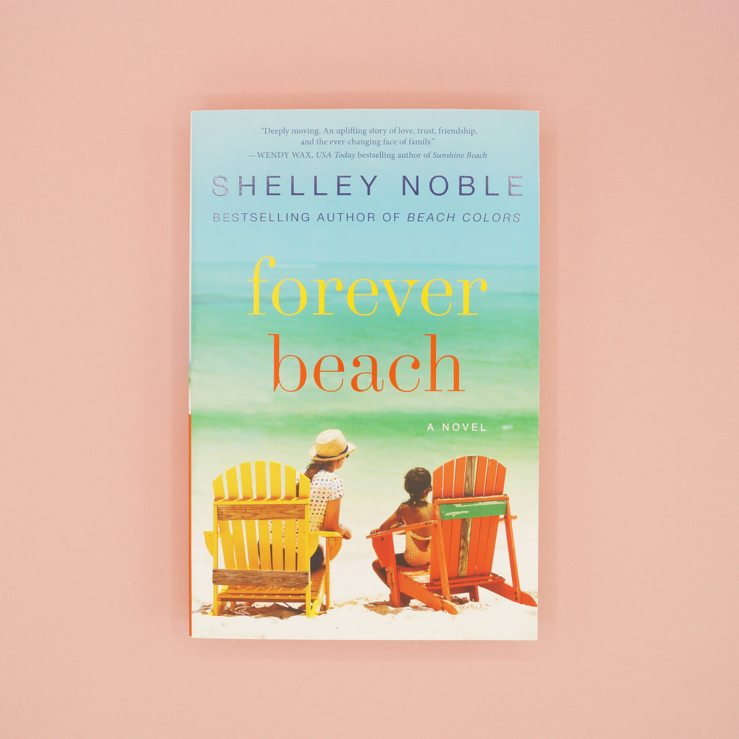 A paperback copy of Forever Beach by Shelley Noble sits on a pink background.