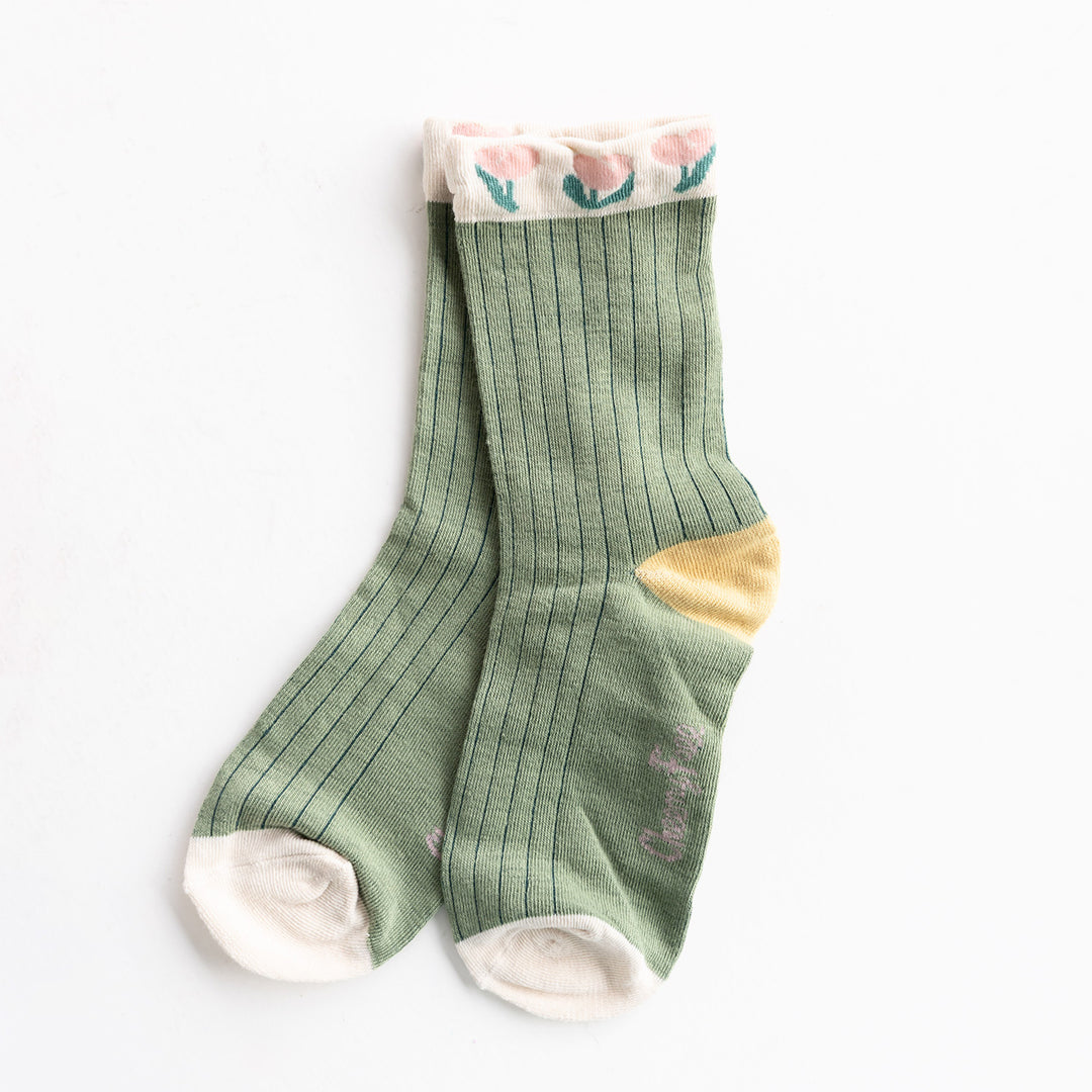 A pair of green socks with a pink tulip pattern on the tops and a yellow heel.