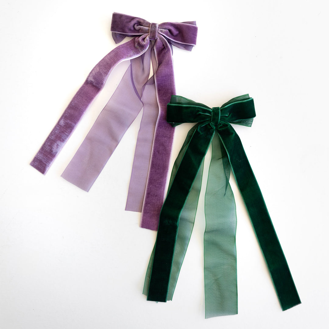 A set of two velvet hair bows, one purple and one dark green.