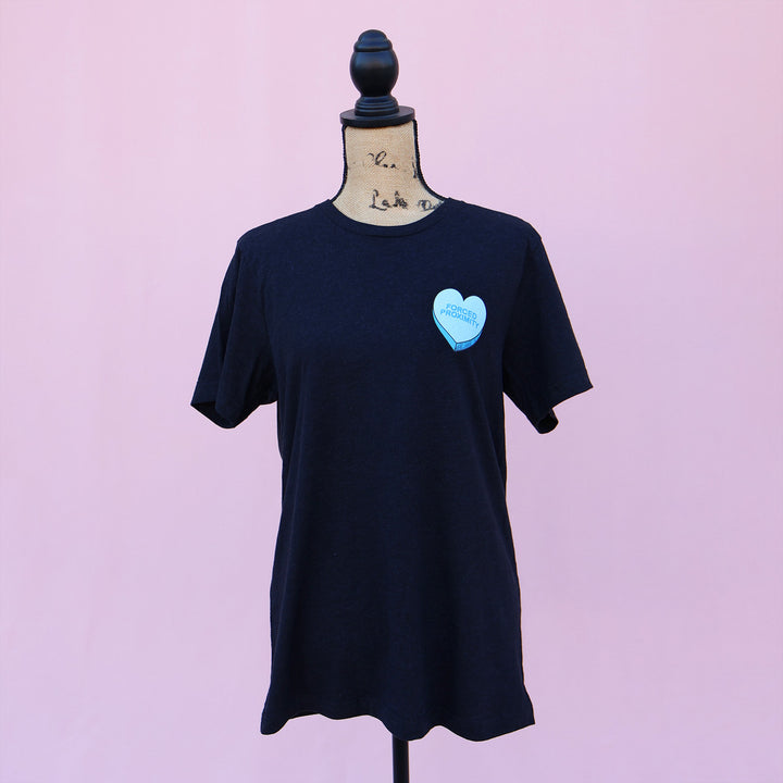 Black t-shirt with a blue heart-shaped candy design and 'Forced Proximity' text on a pink background.