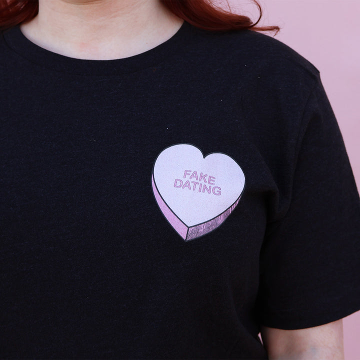 Black t-shirt with a pink heart-shaped candy design and 'FAKE DATING' text on a pink background.