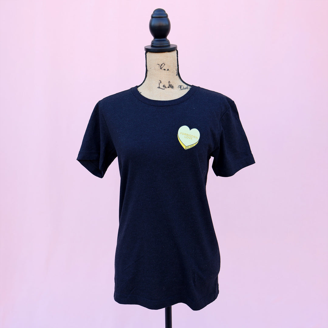 Black t-shirt with a yellow "forbidden love" heart design on a mannequin against a pink background