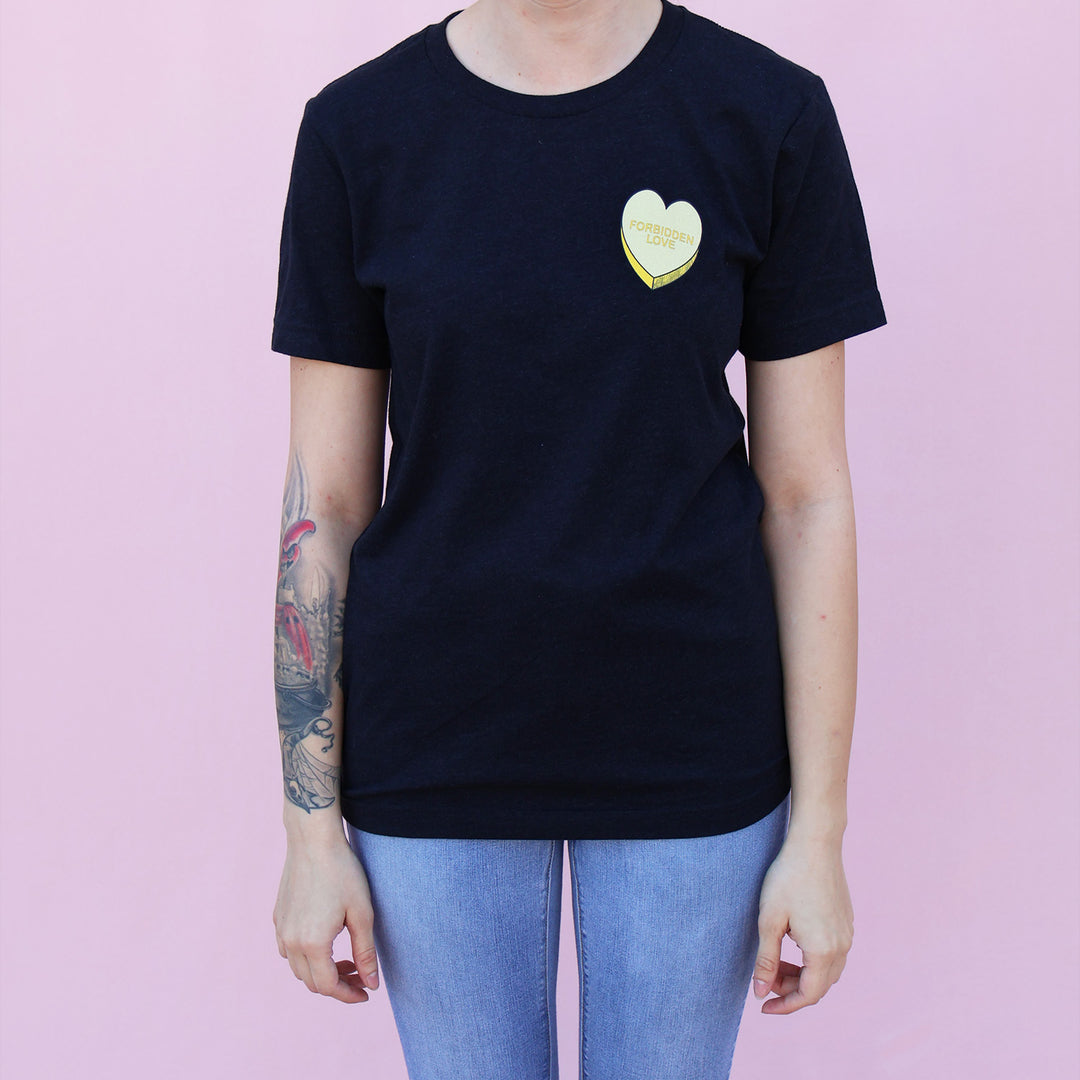 Person wearing a black t-shirt with a yellow heart design on a pink background