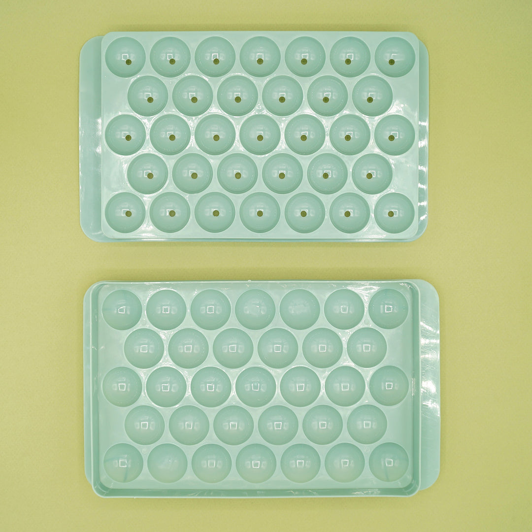 two pieces of a pale green ice ball tray