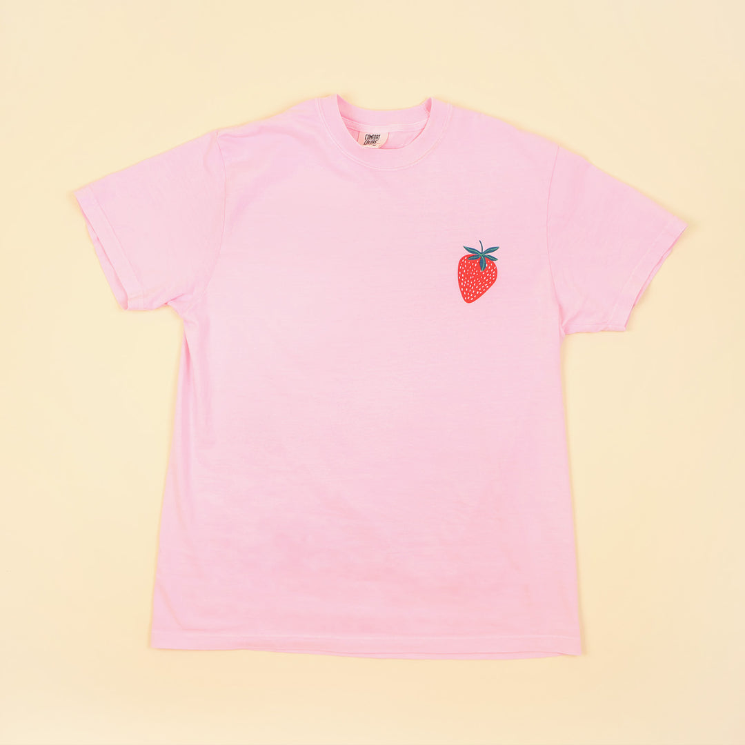 Pink t-shirt with a strawberry graphic on a beige background