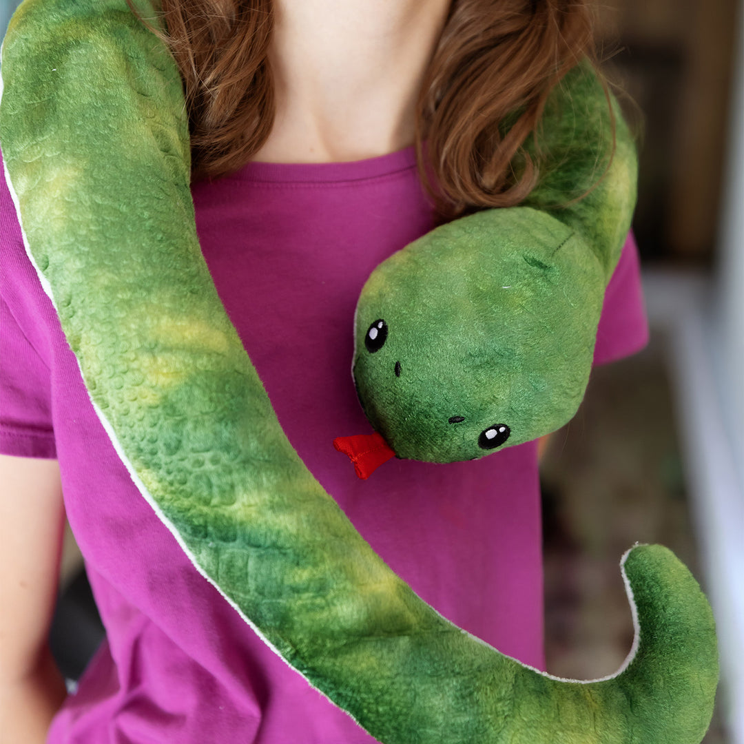 A girl wearing a hot pink shirt wears a plush green snake with a red tongue around her shoulders.