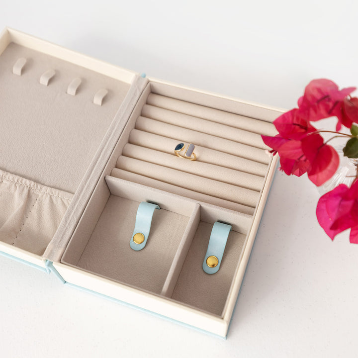 The inside of the book-shaped jewelry box showing the necklace hooks, bracelet clips, and ring/stud earring cushions.