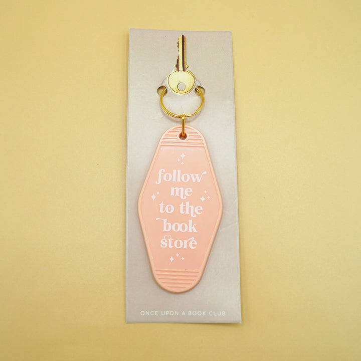 a light peach keychain that says "follow me to the book store" in white writing