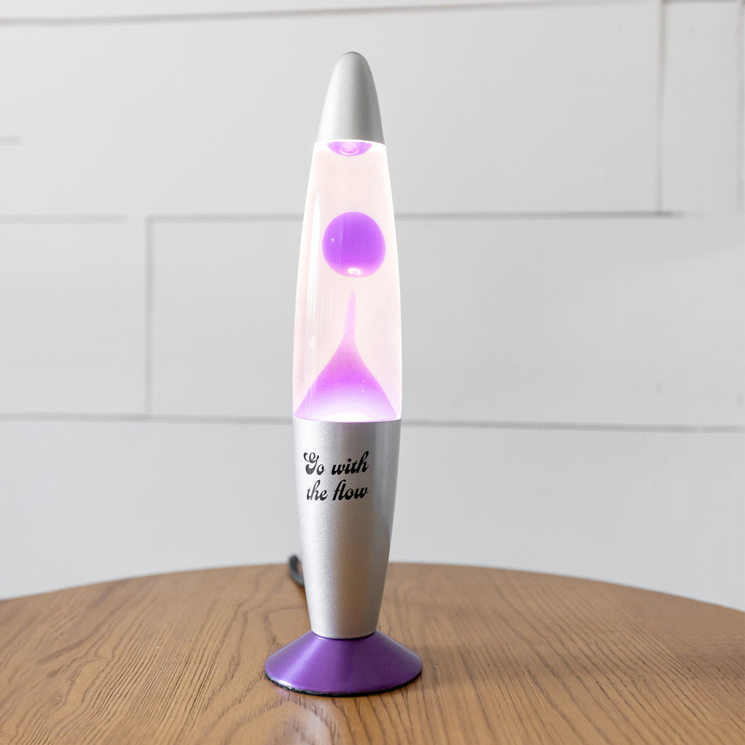 A lava lamp with a purple base and purple lava inside. On the silver outside it says Go With the Flow.