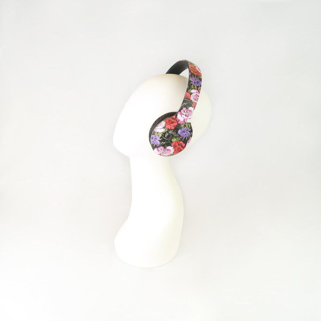 A white mannequin head wears floral headphones in black, pink, red, and purple colors.