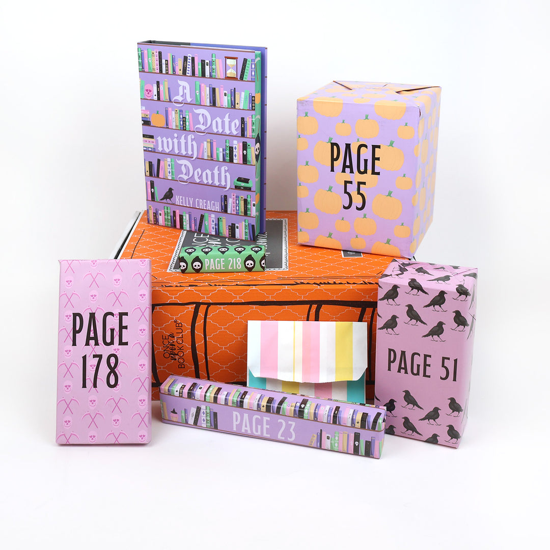 A hardcover special edition with sprayed edges of A Date With Death stands on an orange OUABC Halloween box next to two themed wrapped gifts labeled with page numbers. In front of the box are four more themed wrapped gifts labeled with page numbers.