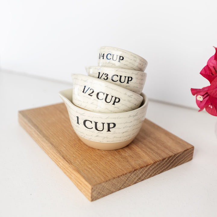 a set of ceramic measuring cups featuring a subtle script writing design.