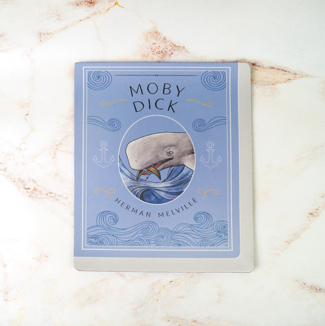 A light blue mouse pad meant to look like the book cover of Moby Dick featuring an illustration of the whale, Moby Dick, in the center. On a pink marbled background.