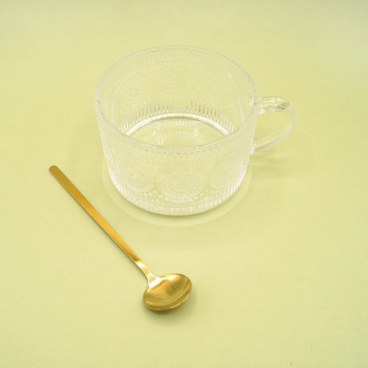 an oversized glass mug and a gold spoon.